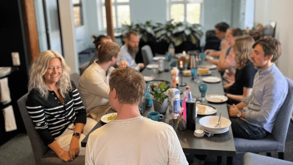 Colleagues sharing lunch at a long table in the office