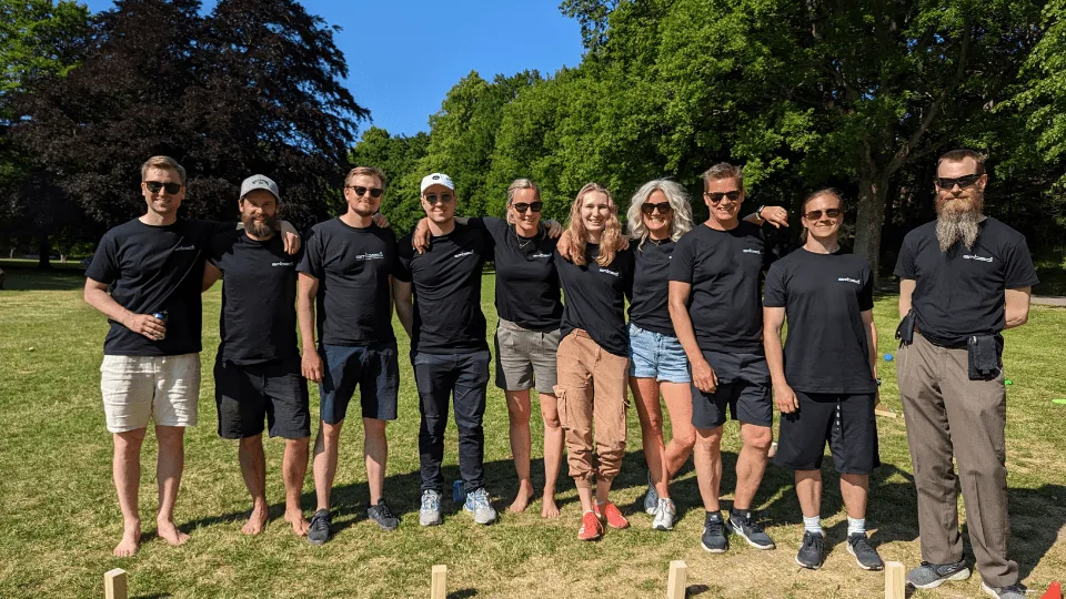 The Embedl team in matching black t-shirts on a sunny lawn